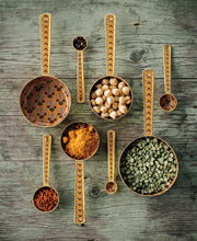 Set of enameled measuring spoons with spices on a wooden surface