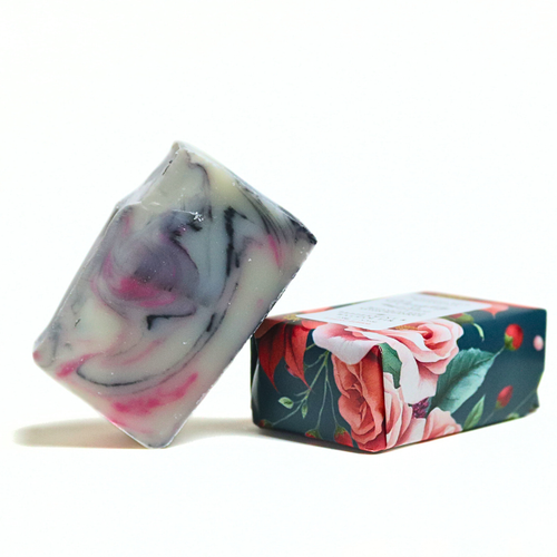 A rectangular bar of marbled soap with swirls of white, pink, and gray, shown standing next to its floral-patterned packaging box on a white background.