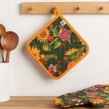 Floral-patterned pot holder and trivet hanging on a wooden rack.