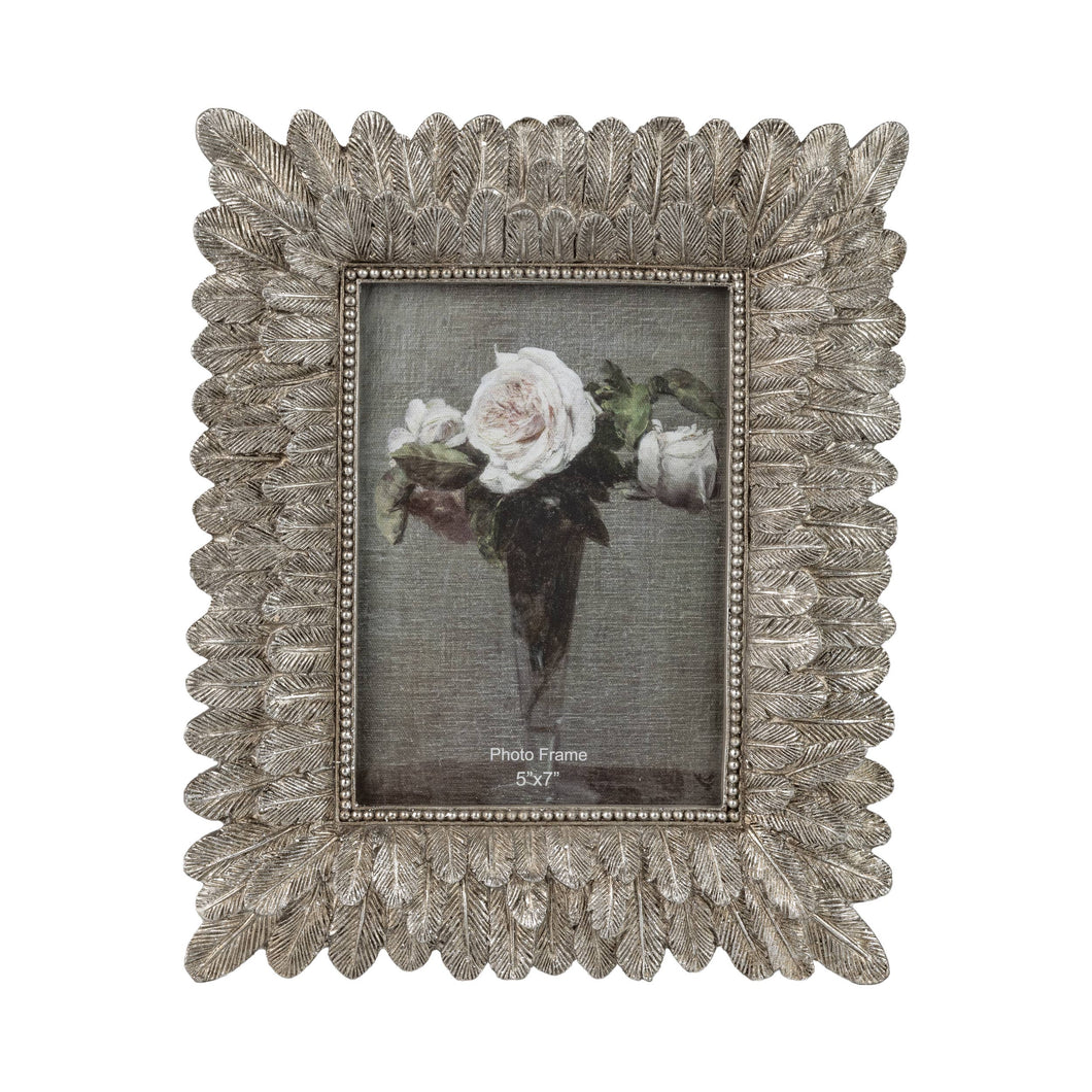 A decorative rectangular photo frame with an ornate leaf-like scalloped border in a distressed silver finish. The frame is shown holding a floral print, photographed against a solid white background.