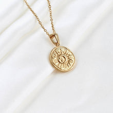 Gold necklace with a sun pendant on a white background