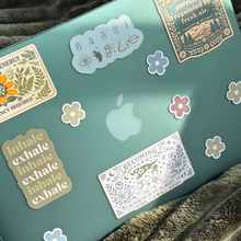 Laptop with various stickers on a green surface
