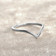 Silver ring with a wavy design on a light beige background