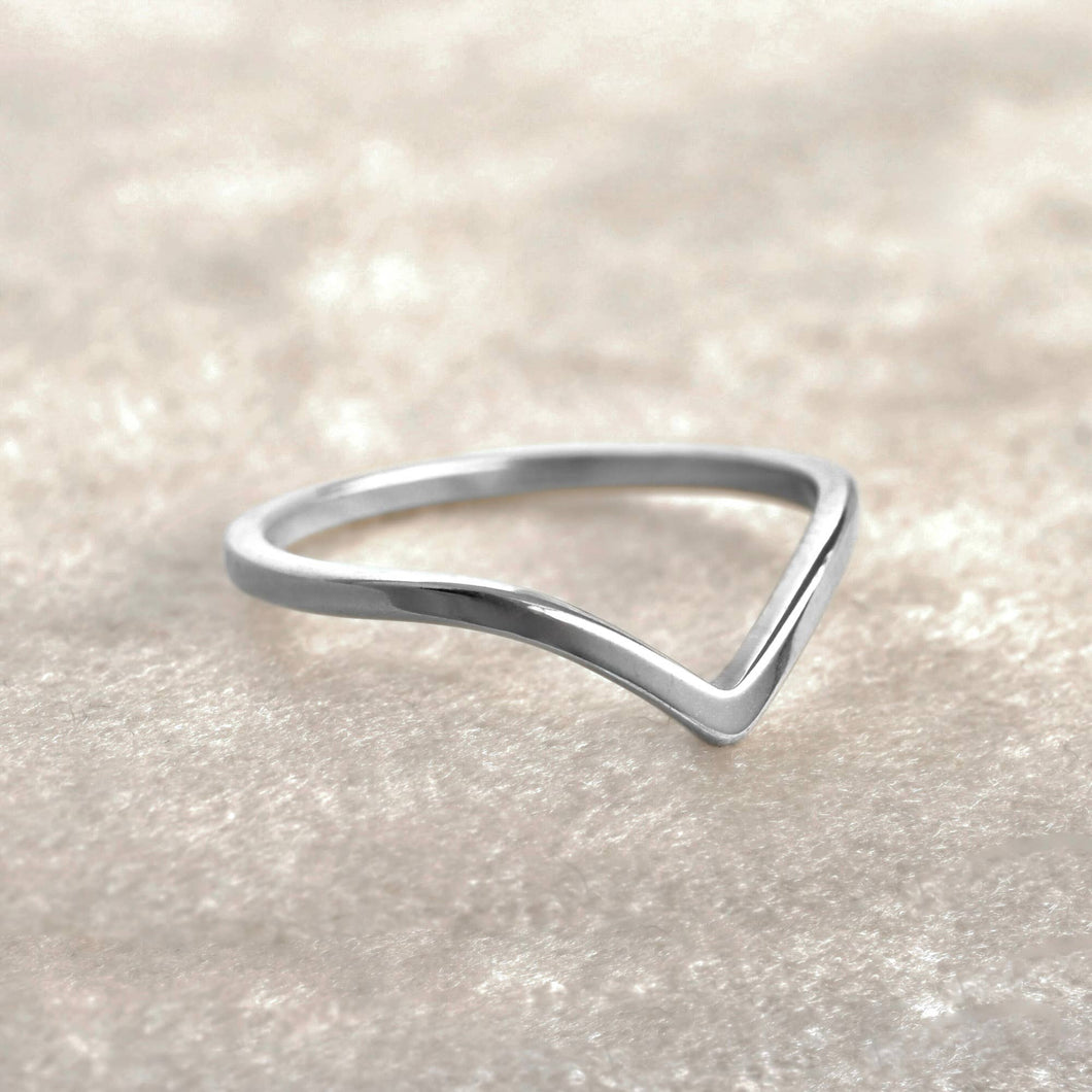 Silver ring with a wavy design on a light beige background