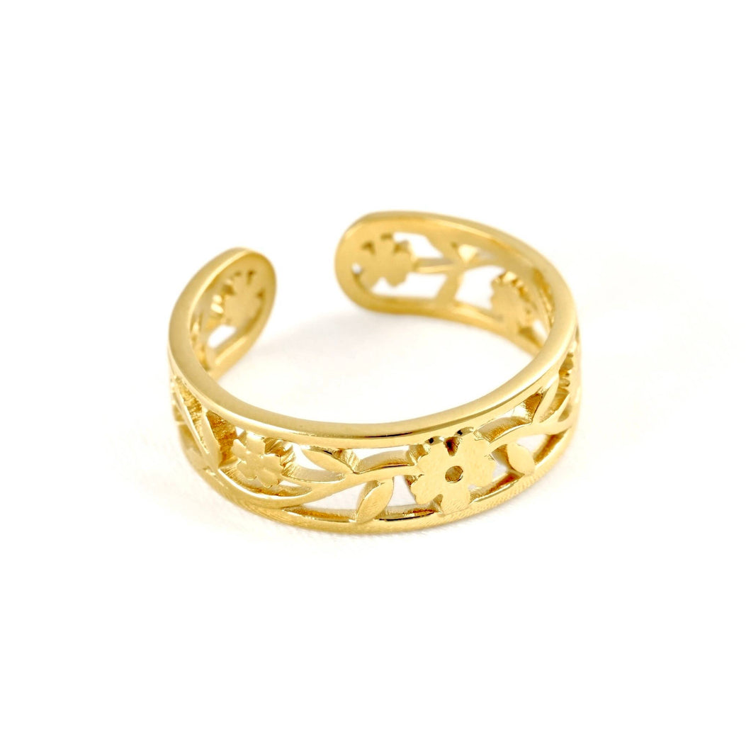 A gold-colored open bangle ring with an intricate filigree floral pattern, displayed on a clean white background.