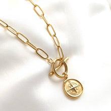Gold necklace with a compass pendant on a white background