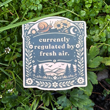 Sticker with nature-themed design and text 'currently regulated by fresh air' on grass.