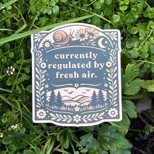 Sticker with nature-themed design and text 'currently regulated by fresh air' on grass.