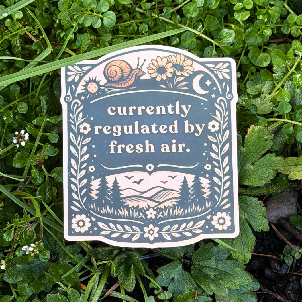 Sticker with nature-themed design and text 'currently regulated by fresh air' on grass.