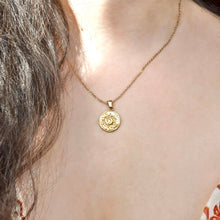 Gold necklace with a circular pendant worn by a person