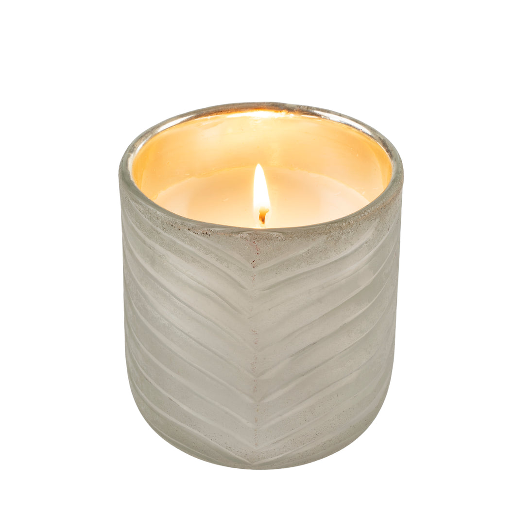Candle in a textured glass holder on a white background