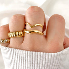 Close-up of a hand wearing multiple gold rings on a white background