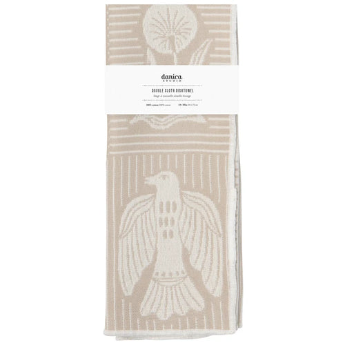 A folded double-cloth dishtowel by Danica, featuring a cream-colored bird and geometric patterns on a warm beige background, wrapped with a white paper label.