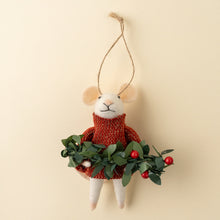 Felt mouse in red sweater holding a bough of greens on beige background