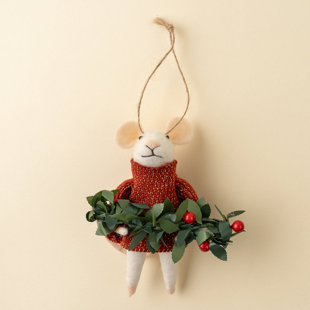 Felt mouse in red sweater holding a bough of greens on beige background