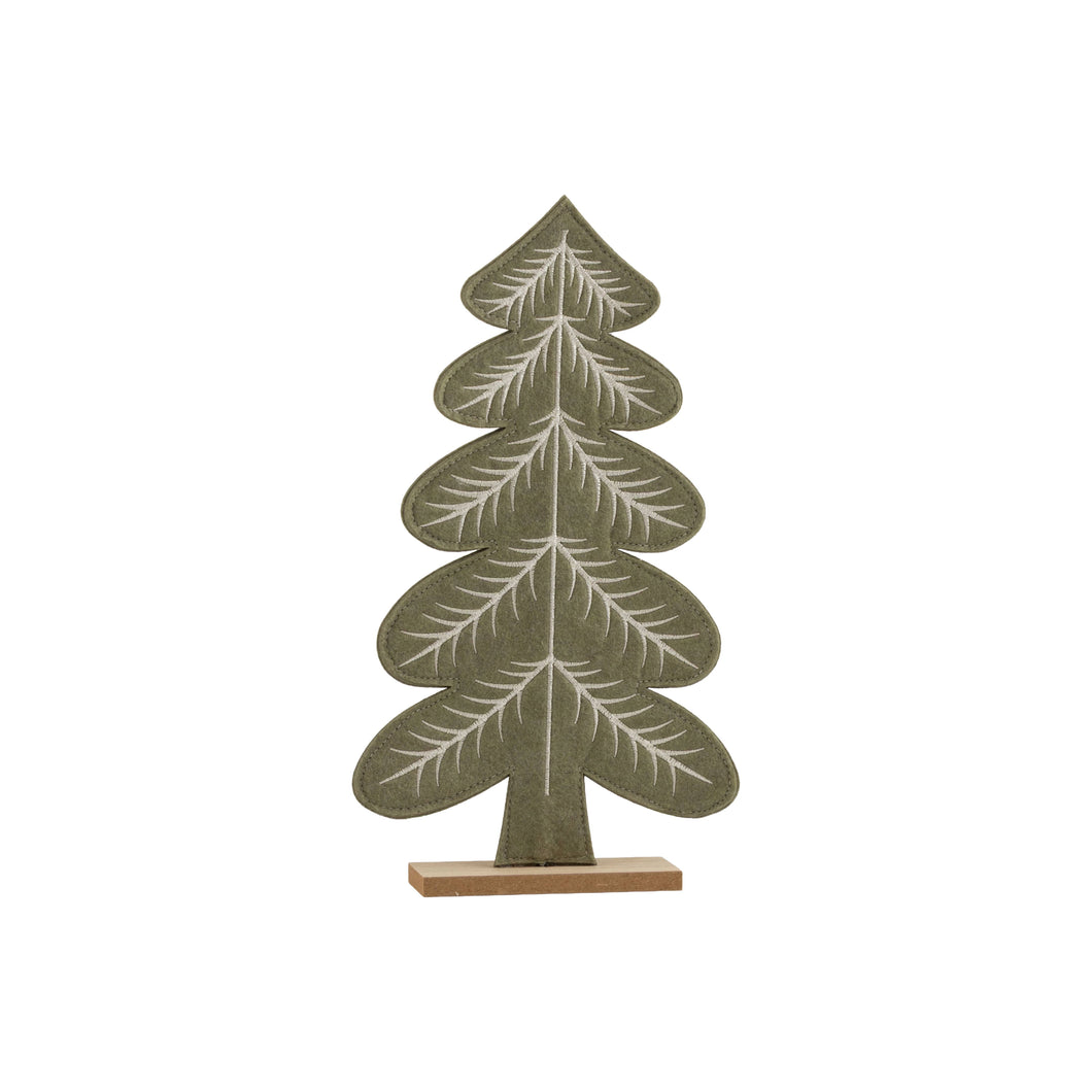 A decorative tree-shaped tabletop sculpture with layered pine-branch motifs, finished in muted sage green with white branch detailing and mounted on a light natural wood base, shown against a plain white background.