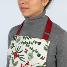 Person wearing a floral apron with red straps on a plain background