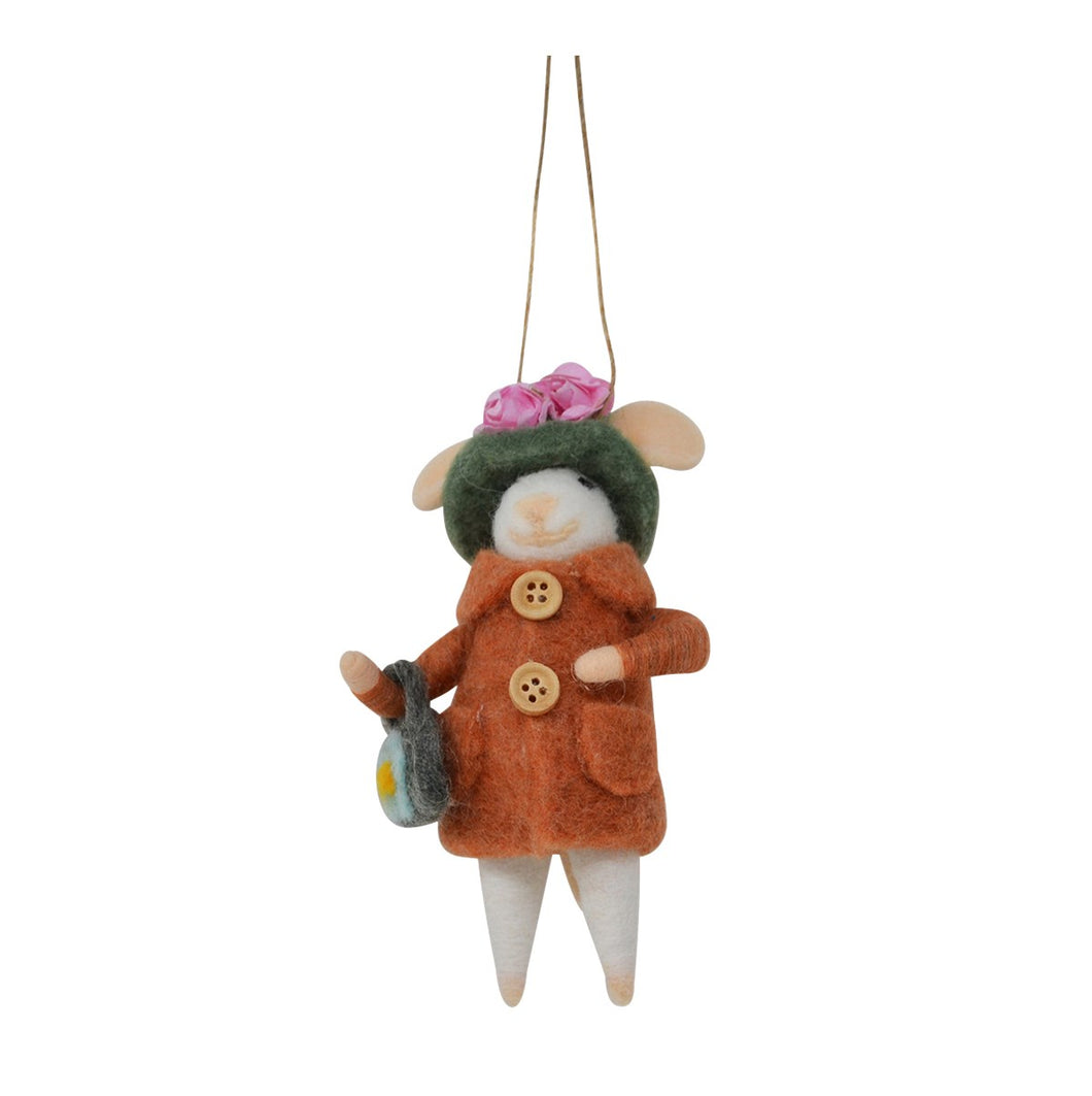 A felted wool mouse ornament dressed in an orange coat with wooden buttons, a green hat with pink flowers, and white legs, hanging by a string against a white background.