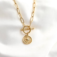 Gold necklace with a compass pendant on a white background