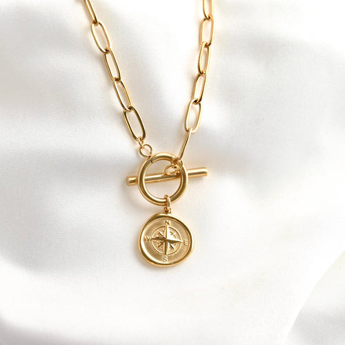 Gold necklace with a compass pendant on a white background