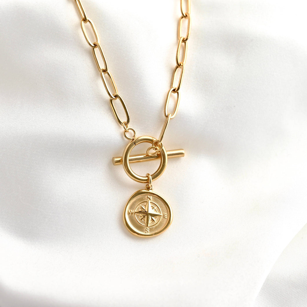 Gold necklace with a compass pendant on a white background