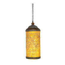 A hanging pendant light with a cylindrical glass shade, featuring a warm yellow glow from within and an ornate bronze-toned metal frame with decorative cutouts and bands, suspended by a chain against a plain white background.