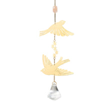 Decorative hanging with gold bird shapes, star, and crystal on a gray background