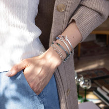 Person wearing multiple bracelets on a wrist with a blurred background