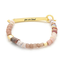 Bracelet with multicolored beads and gold clasp with text you are loved on a white background