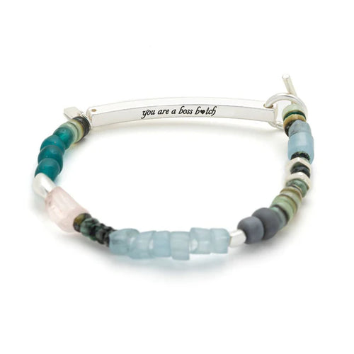 Beaded bracelet with a silver bar and 'you are a boss bitch' engraving on a white background