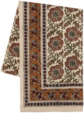 Decorative table cloth with floral patterns in rust, green, and beige on a white background