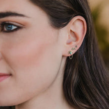 Close-up of a woman's ear wearing a small earring with a blurred background