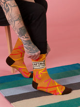 Person wearing colorful socks with a brand logo on a striped rug.