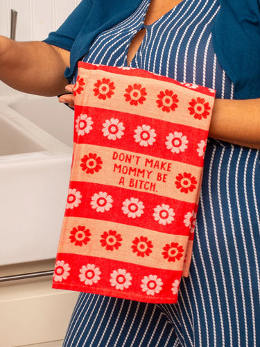 Person holding a red and white patterned towel with text in a kitchen setting