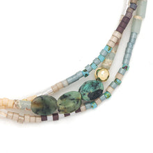 Multistrand beaded bracelet with turquoise stones and gold accents on a white background