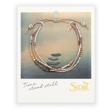 Bracelet with stones on a scenic background, featuring the phrase 'time stood still' and 'Scout' brand.