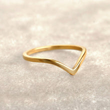 Gold triangle ring on a light beige background