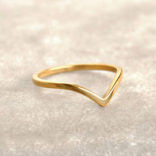 Gold triangle ring on a light beige background