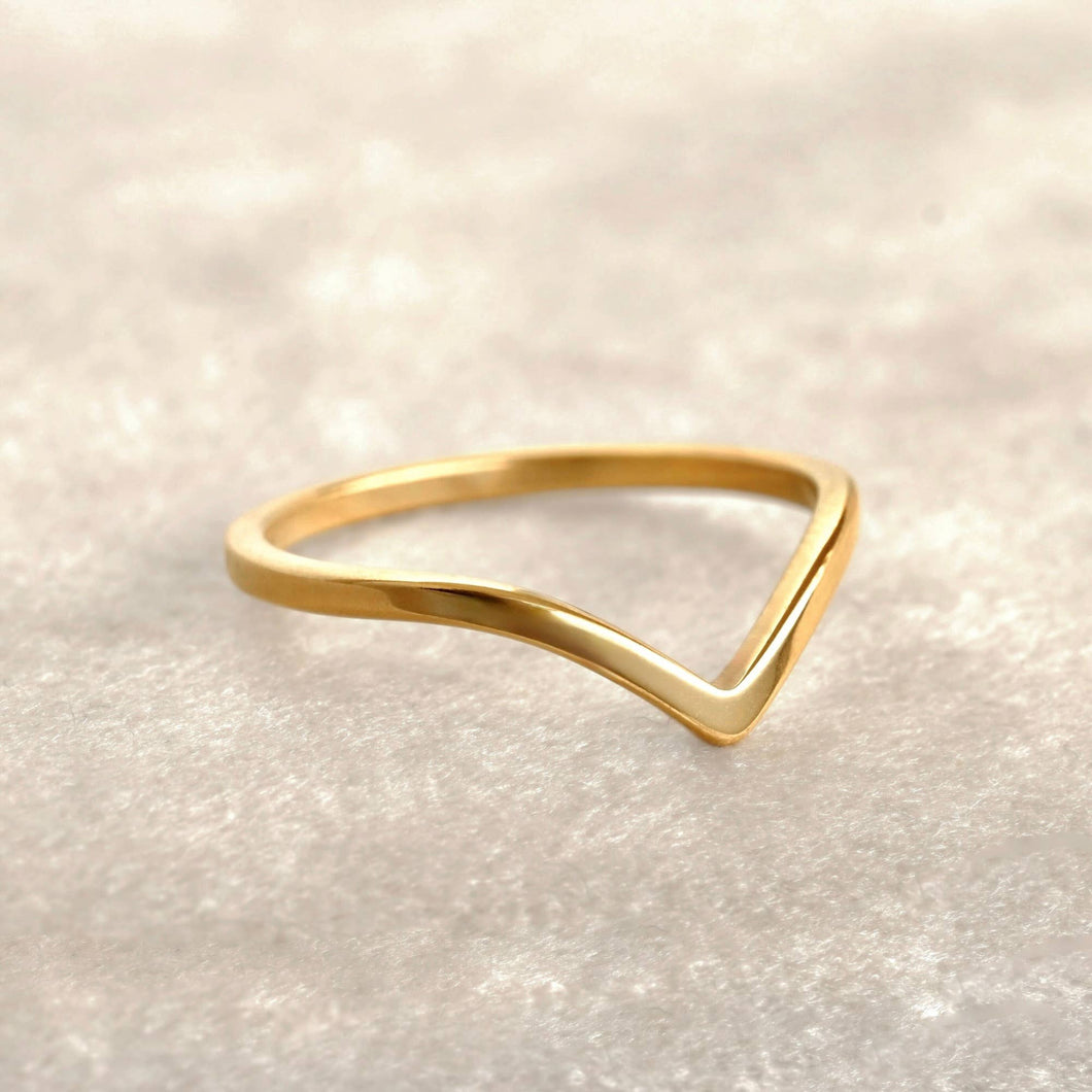 Gold triangle ring on a light beige background