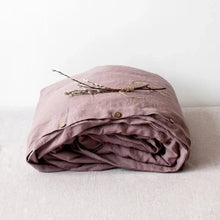 Folded mauve duvet cover with wooden buttons on a light background