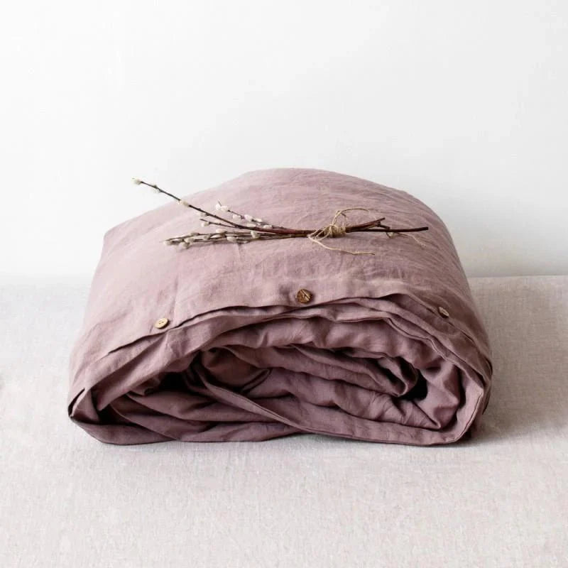 Folded mauve duvet cover with wooden buttons on a light background