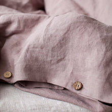 Close-up of a mauve duvet cover with wooden buttons on a soft focus background