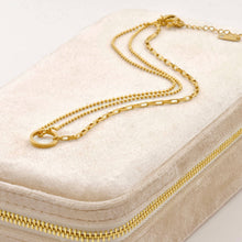 Gold chain necklace on a beige jewelry box
