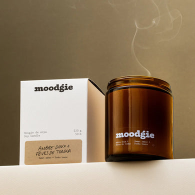 Brown candle with 'moodgie' branding next to its gift boxed packaging against a neutral background