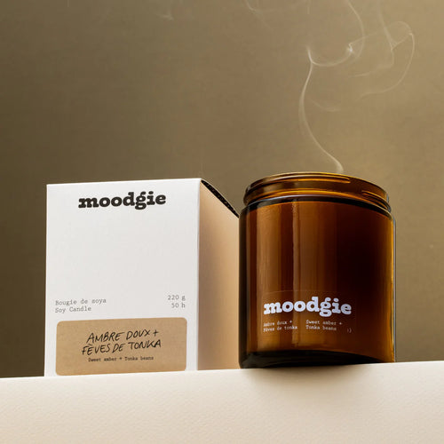 Brown candle with 'moodgie' branding next to its gift boxed packaging against a neutral background