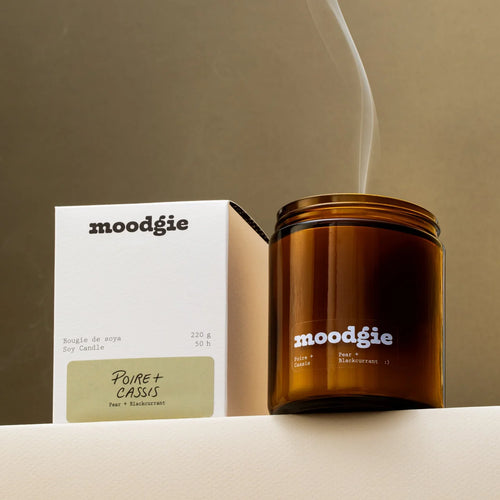 Brown candle with 'moodgie' branding and packaging on a beige background
