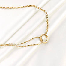 Gold necklace with a small circular pendant on a light background