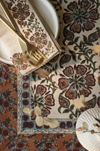 Decorative table setting with patterned placemats and cutlery on a textured surface.
