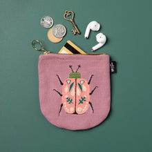 Pink coin purse with beetle design on a green background