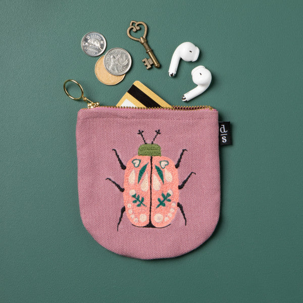 Pink coin purse with beetle design on a green background